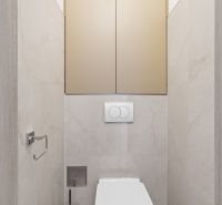 A toilet in a 3-room apartment with neutral-colored tiles and elegant lines.