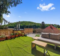 Terrace with a view of greenery, sofa, swing, and potted plants.