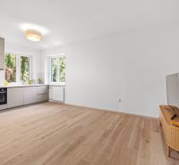 A spacious kitchen in a 3-room apartment with a wooden decor floor and minimalist furniture.