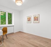 A room in a 3-room apartment with a wooden decor floor and wall paintings.