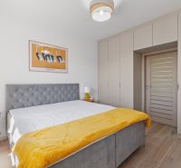 Bedroom with a bed, yellow blanket, painting, and a large built-in wardrobe in a 3-room apartment.