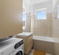 Bathroom with a bathtub, washing machine, and sink in a 3-room apartment.
