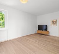 Living room in a 3-room apartment with a TV, cabinet, and wooden decor flooring.