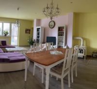 Living room in a family house, light walls, large purple sofa, dining table.