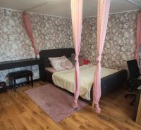 A bedroom in a family house with romantic pink details and a wood-patterned floor.