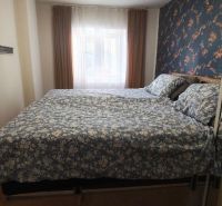 A bedroom in a family house with floral wallpaper and a wooden decor floor.