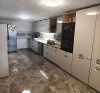 A kitchen with a glossy floor, white cabinets, and appliances in a family house.