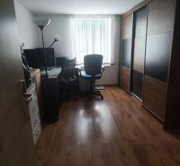 A home office with a wood-patterned floor and a large wardrobe in a family house.