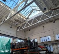 Production spaces with large windows and steel structures under skylights.