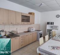 A kitchen unit in a production area with a wooden decor floor and a table with a tablecloth.