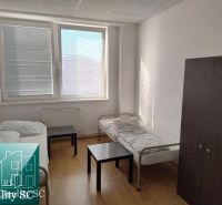 A room with a light wooden floor, beds, and dark furniture in warehouses and halls.