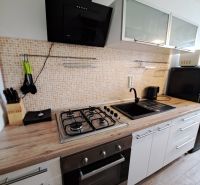 A kitchen in a 3-room apartment with a gas stove and a wooden decor floor.