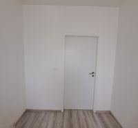A white room in a 3-room apartment with wood-patterned flooring and white doors.