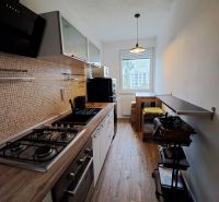 A kitchen with a wooden decor floor and a view, furnished in a 3-room apartment.