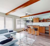 Living room in a family house with a kitchen, wooden decor flooring, and comfortable seating.