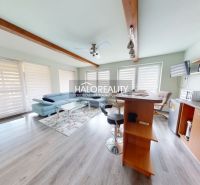 Living room in a family house with a wooden decor floor, sofa, and kitchen counter.