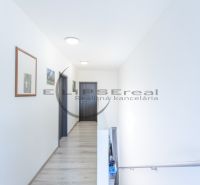 A hallway with light walls, doors, and a floor with a wooden decor in a family house.