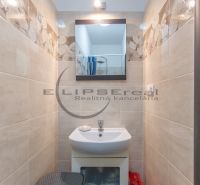 A small bathroom in a family house with a sink, a mirror, and floral tiles.