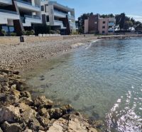 The coast near three-story buildings in Sukošan, ideal for a three-bedroom apartment with a view.