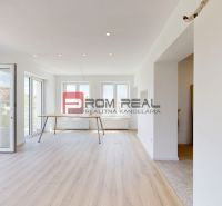 Interior of a family house with a wooden-patterned floor and large windows.