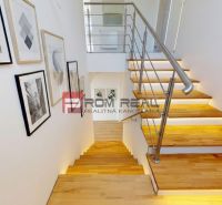 A staircase with a wooden decor floor in a family house, adorned with paintings.