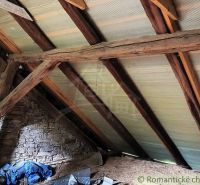 The attic of the cottage with wooden beams and a stone wall.