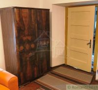 A wooden cabinet by the door and an orange couch in the cabin.