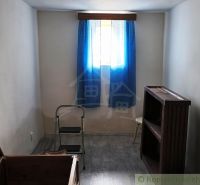 A room in a cottage with a blue curtain, stairs, and a floor with a wooden decor.