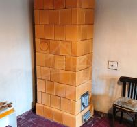 Tiled stove, wooden chair, and floor with wooden decor in the cabin.
