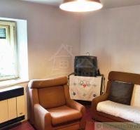 Living room in a cottage with armchairs, a television, and traditional decorations.