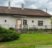 A cottage in Hermanovce with a garden, a fence, and an older facade, under a cloudy sky.