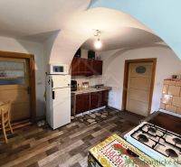 A kitchen in a cottage with a wooden decor floor and a tiled stove.