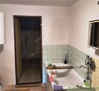 A bathroom in a cottage with a bathtub, tiles, and an electric boiler.