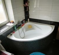 A bathroom with a separate bathtub in a 3-room apartment, complemented by black tiles.