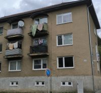 An apartment building in Snina with balconies and drying laundry, located by the street.