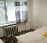 Bedroom in a 3-room apartment with a bed and a radiator, floor with wooden decor.