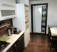Kitchen in a 3-room apartment with a cooktop, dining table, and floor with a wooden decor.