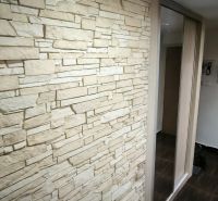 Stone cladding and mirrored doors in the entrance hallway of a 3-room apartment.