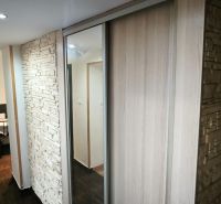 A hallway with stone cladding and a mirrored wardrobe in a 3-room apartment.