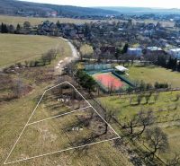 A plot for residential purposes in Hodkovce surrounded by greenery and a tennis court.
