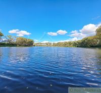 A lake surrounded by trees in Hruboňovo in Záhrady under a clear blue sky.