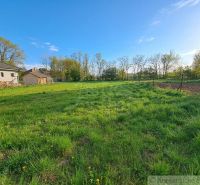 Vast green gardens in Hruboňovo surrounded by trees and houses on a sunny day.