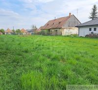 Family houses in Hruboňovo surrounded by green gardens and blue skies.