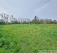 A vast green meadow surrounded by trees and fencing in the Gardens near Hruboňovo.