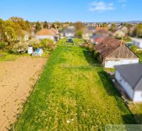 Gardens in Hruboňovo with a lawn, house, and field in the background.