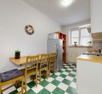 A kitchen in a studio apartment with a dining area, linoleum flooring, and appliances.