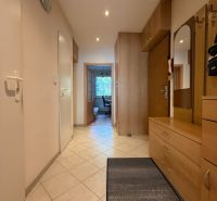 A hallway in a 3-room apartment with tiles and wooden furniture.