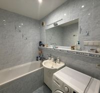 Bathroom in a 3-room apartment with a bathtub and a washing machine, bright tiles.