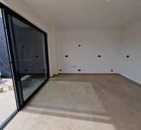 Interior of a holiday apartment with large glass doors and tiled floor.