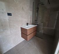 A bathroom in a holiday apartment with ceramic tiles and a shower enclosure.